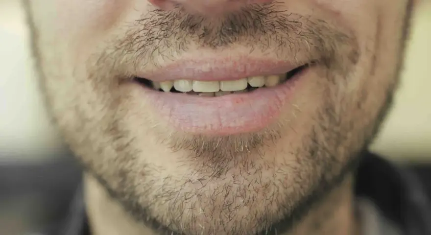 Un sourire d'homme barbu, peut-être réfléchissant au coût des études de dentiste pour un avenir radieux.