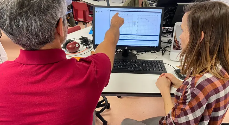 Un homme montre un audiogramme à une femme, lors d'une formation audioprothésiste Espagne à distance.