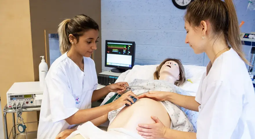 Étudiantes en sage-femme en Belgique pratiquant sur un mannequin de grossesse.
