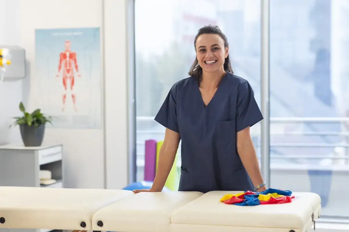 Une &eacute;tudiante souriante en uniforme de kin&eacute;sith&eacute;rapeute, pr&ecirc;te pour sa formation &agrave; l'&eacute;cole de kin&eacute; en Espagne.