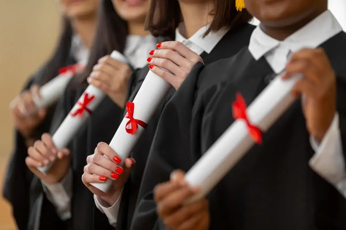 Diplômés en toges noires, tenant des parchemins avec des rubans rouges. Une réussite pour une licence science politique à distance.