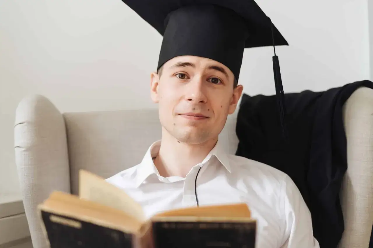 Dipl&ocirc;m&eacute; en intelligence artificielle, un jeune homme en toque et robe de c&eacute;r&eacute;monie lit un livre ancien, pr&ecirc;t &agrave; explorer de nouveaux horizons.