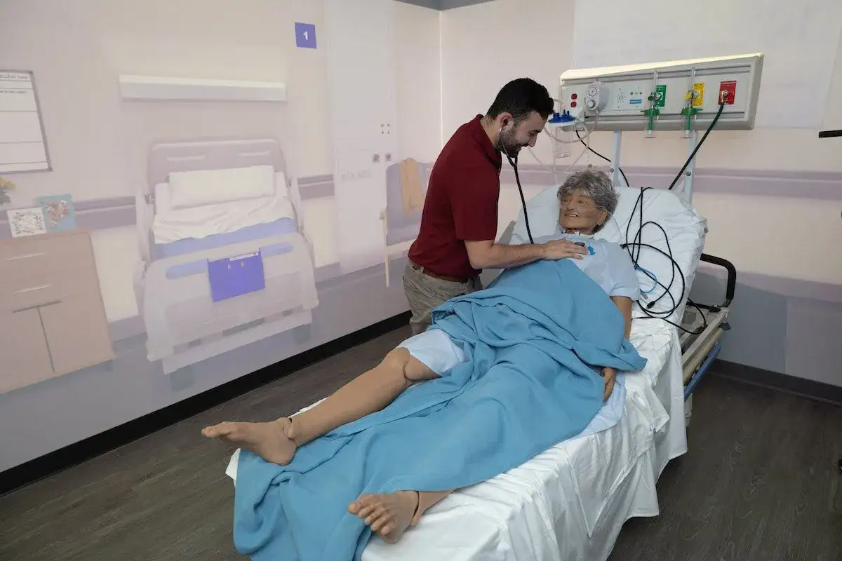 Un &eacute;tudiant en kin&eacute;sith&eacute;rapie de l'&eacute;cole kine Manresa pratique l'auscultation sur un mannequin dans une chambre d'h&ocirc;pital simul&eacute;e.