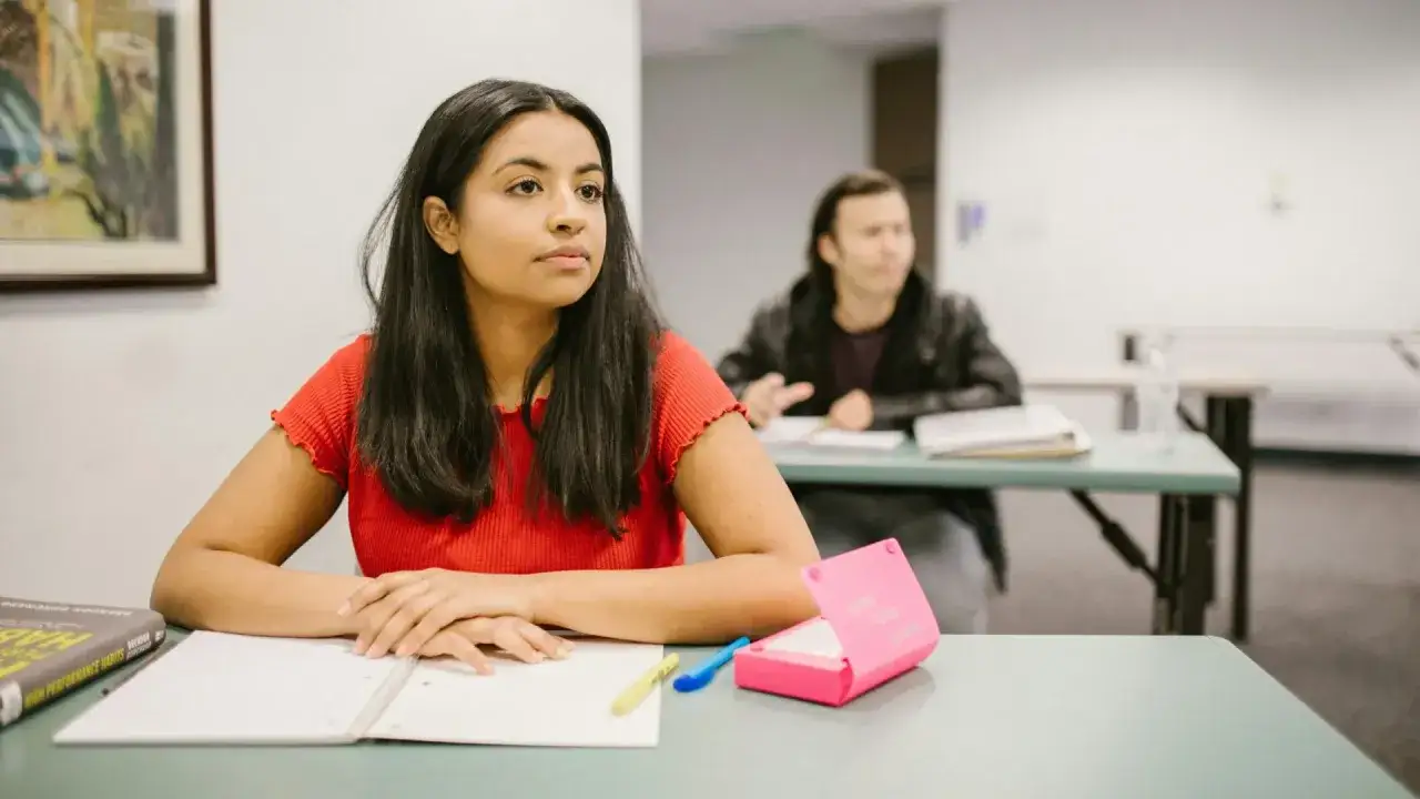 Une jeune femme réfléchit à son année de césure en classe, entourée de livres et de matériel scolaire.