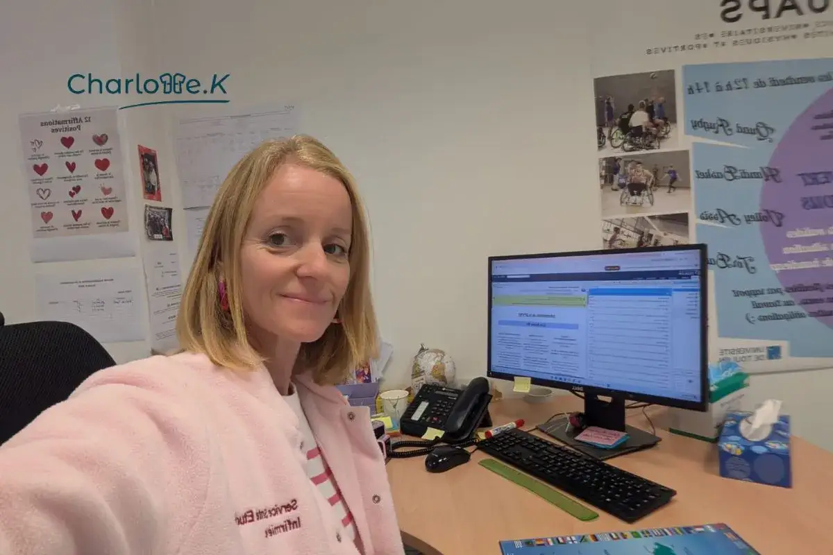 Charlotte, une master infirmier à distance, travaille à son bureau. Elle porte une veste rose et des boucles d'oreilles roses.