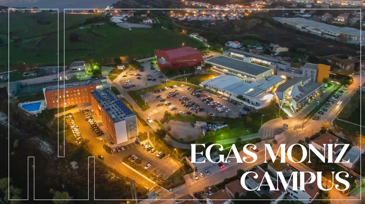 Vue aérienne nocturne du campus Egas Moniz à Lisbonne, avec ses bâtiments modernes et son parking.