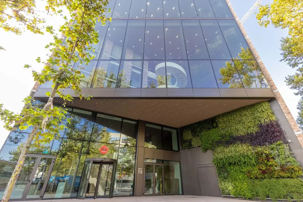 Entrée moderne de eada business school avec mur végétal luxuriant et escalier en colimaçon visible à travers la façade vitrée.