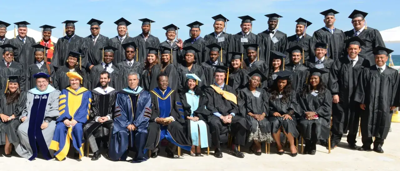 Groupe de diplômés en toges noires, certains portant des capes colorées. Ils célèbrent l'obtention de leur doctorat en commerce international.