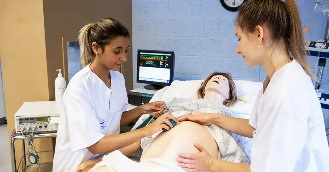 Étudiantes en sage-femme en Belgique pratiquant sur un mannequin de grossesse.