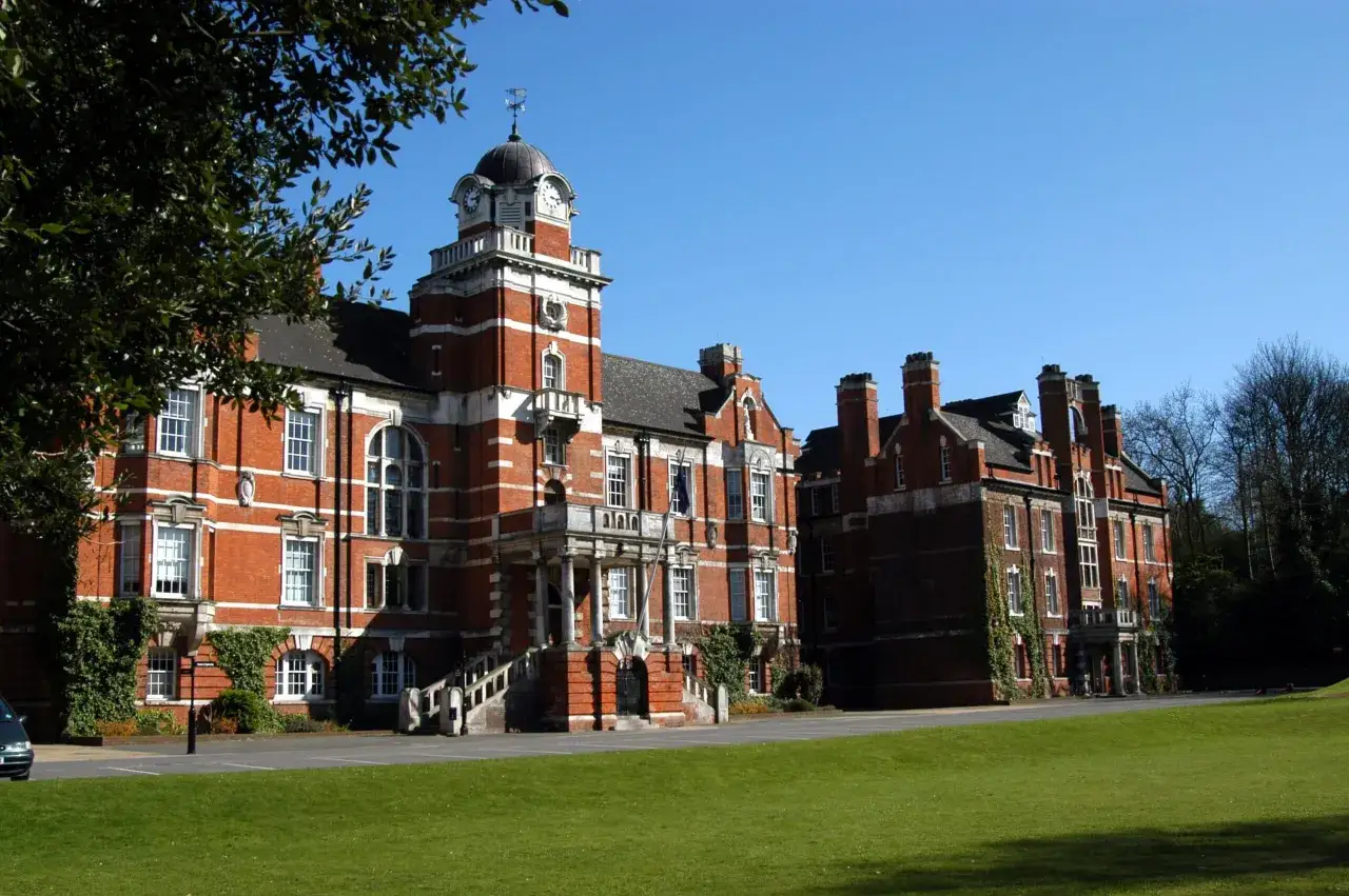 B&acirc;timents en briques rouges avec une tour d'horloge, typiques de l'universit&eacute; de Greenwich, sous un ciel bleu clair.