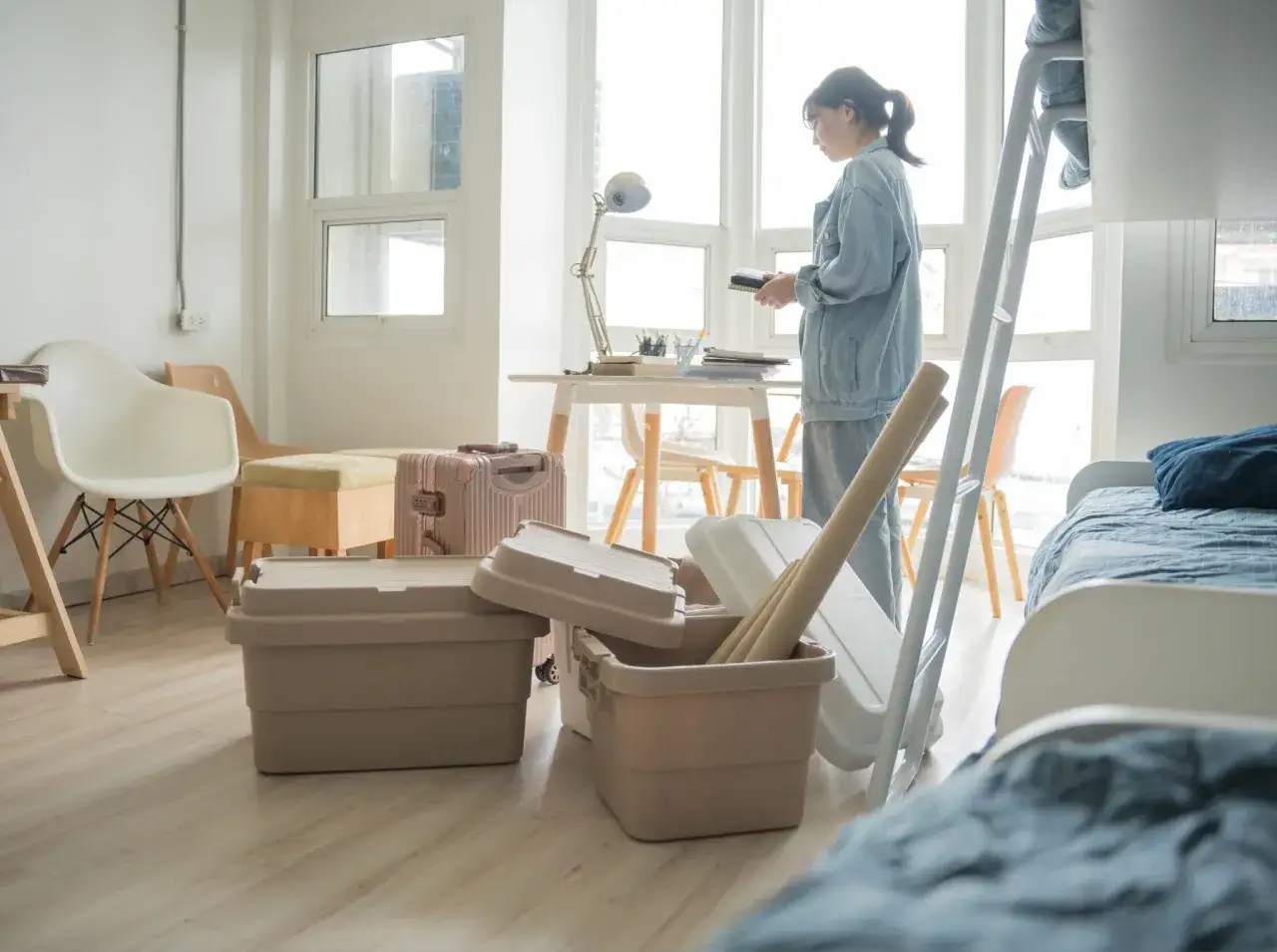 Une jeune femme prépare son déménagement au Canada, entourée de boîtes et de bagages. Ce décor évoque les défis et les espoirs liés au niveau de vie au Canada.