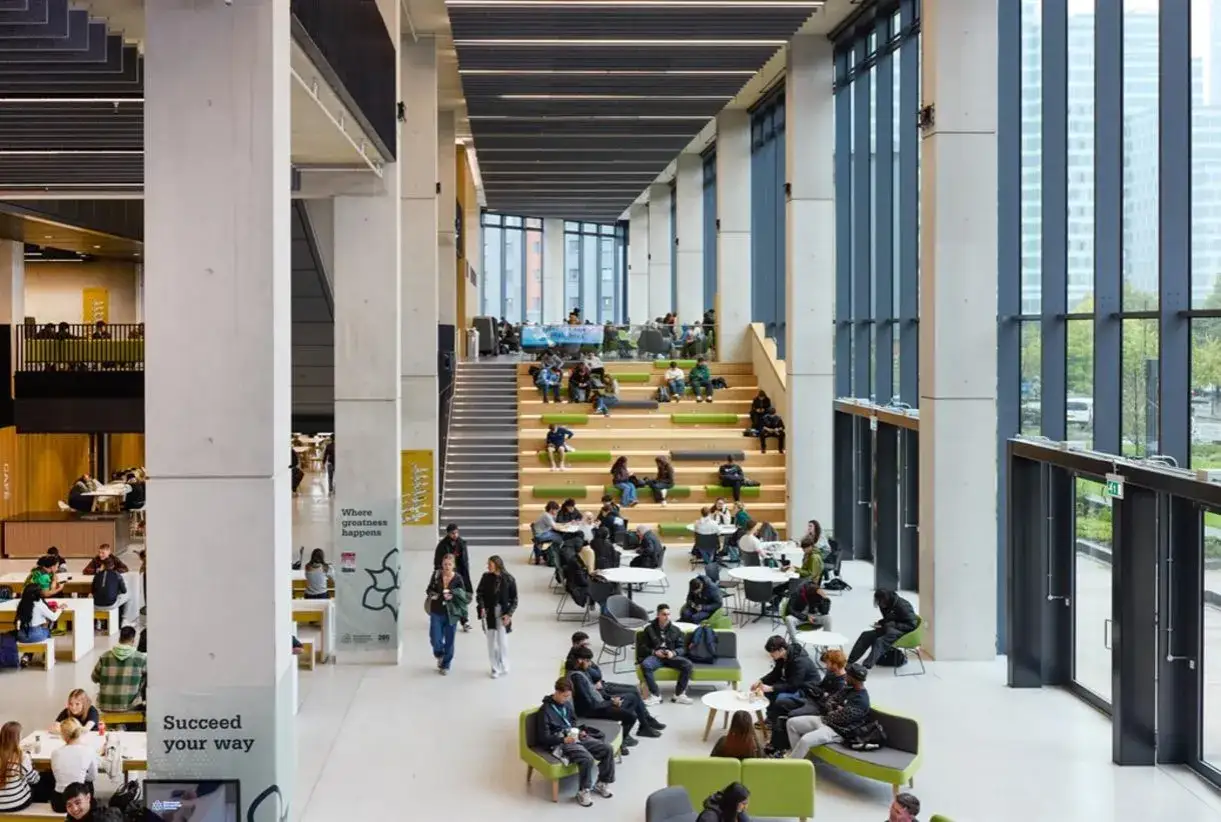 L'universit&eacute; m&eacute;tropolitaine de Manchester, un espace moderne et lumineux o&ugrave; les &eacute;tudiants se d&eacute;tendent et &eacute;tudient sur des gradins verts et des tables.