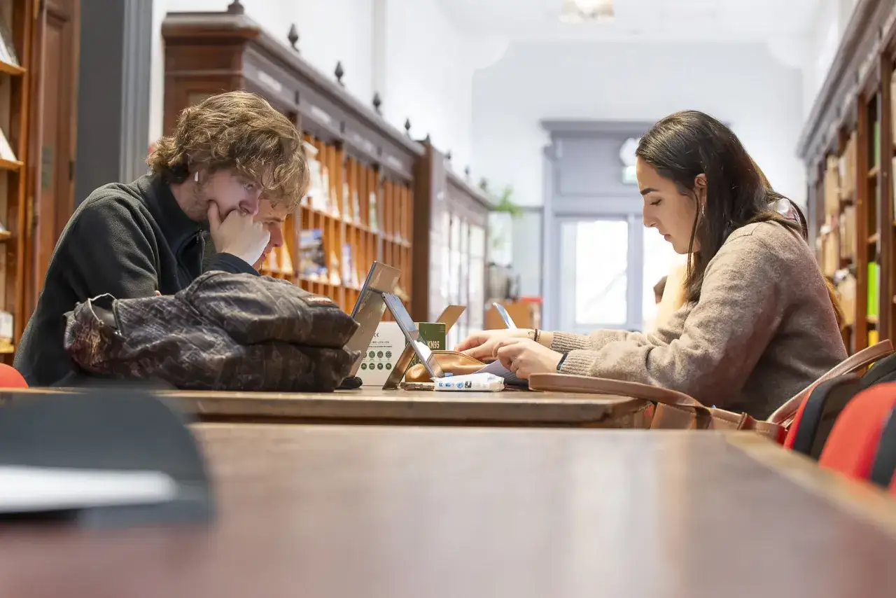 Deux étudiants en journalisme, concentrés sur leurs études, dans une bibliothèque. Combien d'années leur faudra-t-il pour obtenir leur diplôme ?