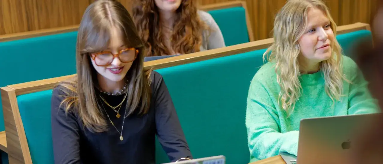Étudiantes en master relations internationales à distance, concentrées sur leurs cours en amphithéâtre.