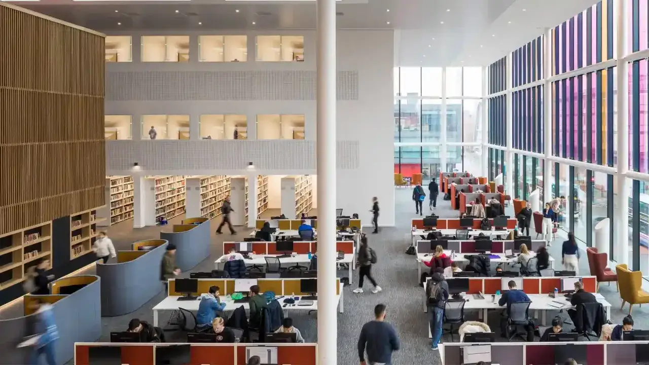 Vaste bibliothèque moderne de l'alliance Manchester Business School, avec étudiants travaillant dans des espaces ouverts et des bureaux.