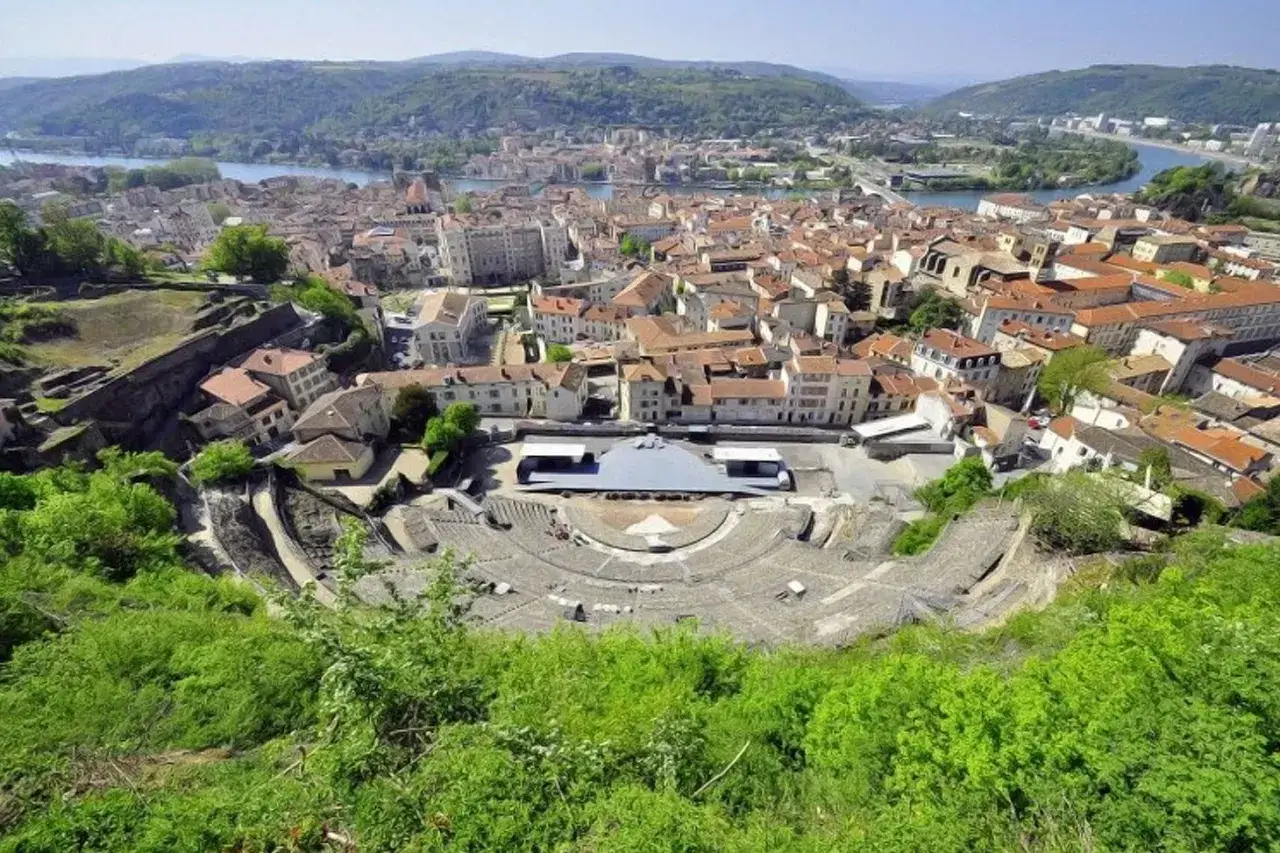 Vue panoramique de l'amphith&eacute;&acirc;tre romain de Vienne, un site historique majeur, avec la ville et le Rh&ocirc;ne en arri&egrave;re-plan. L'&eacute;cole de Vienne, un lieu d'apprentissage et de culture, s'int&egrave;gre dans ce paysage.