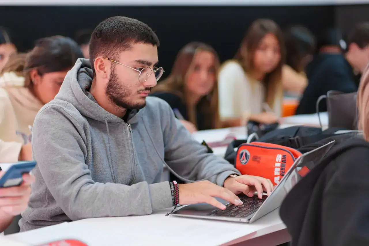 Un étudiant en BTS Audioprothésiste en alternance travaille sur son ordinateur portable, concentré sur ses études.