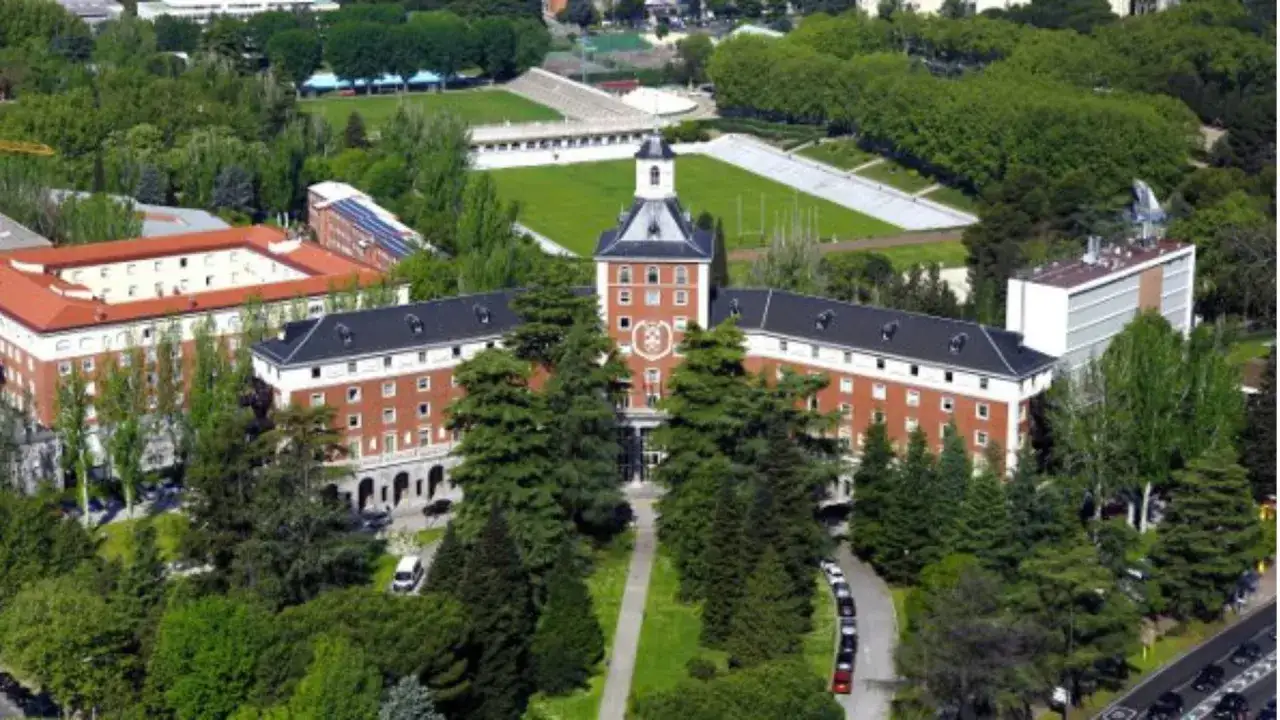 Vue aérienne d'un campus universitaire verdoyant à Madrid, avec des bâtiments en brique et une tour centrale. Un lieu idéal pour un master à Madrid.