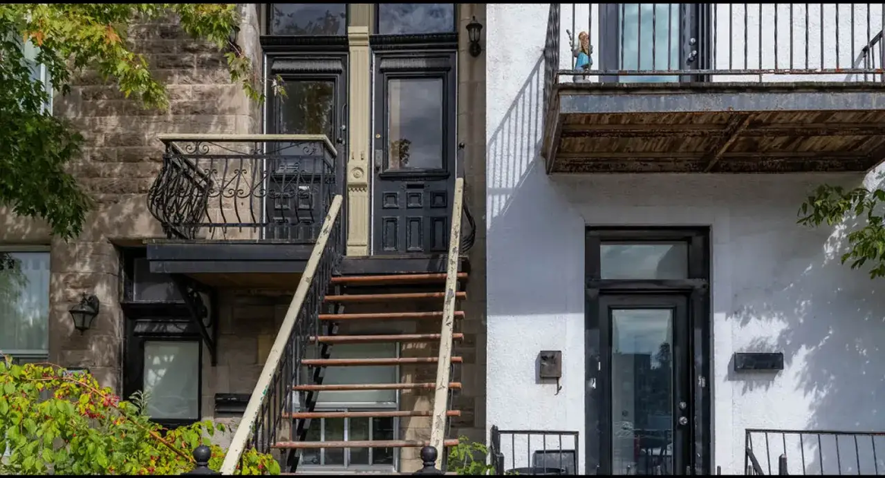Escaliers extérieurs menant à des portes, typiques du logement étudiant au Canada. Une petite figurine est visible sur un balcon.