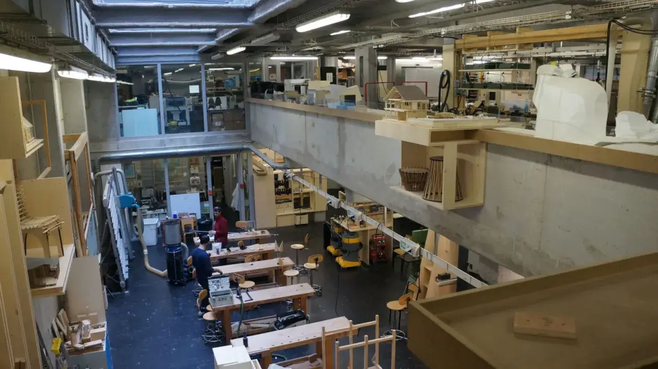 Atelier d'une école d'architecture privée, avec des maquettes, des établis et des outils.