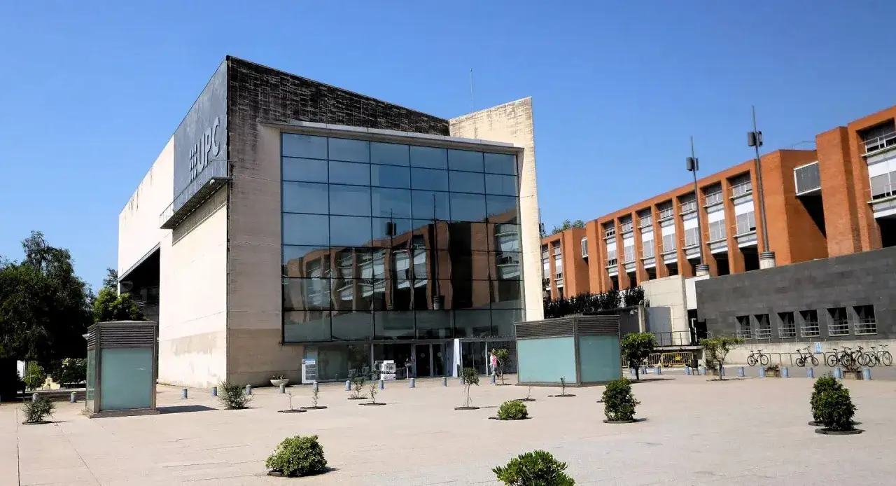 Bâtiment moderne avec le logo UPC, reflet d'un bâtiment en briques. Ce campus est un exemple de l'excellence académique dans le classement université espagne.