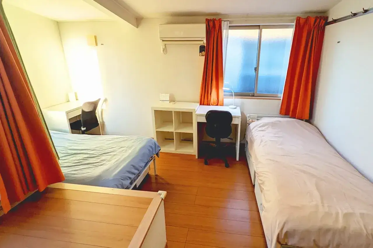 Chambre d'&eacute;tudiant &agrave; Tokyo avec deux lits, bureaux et &eacute;tag&egrave;res.