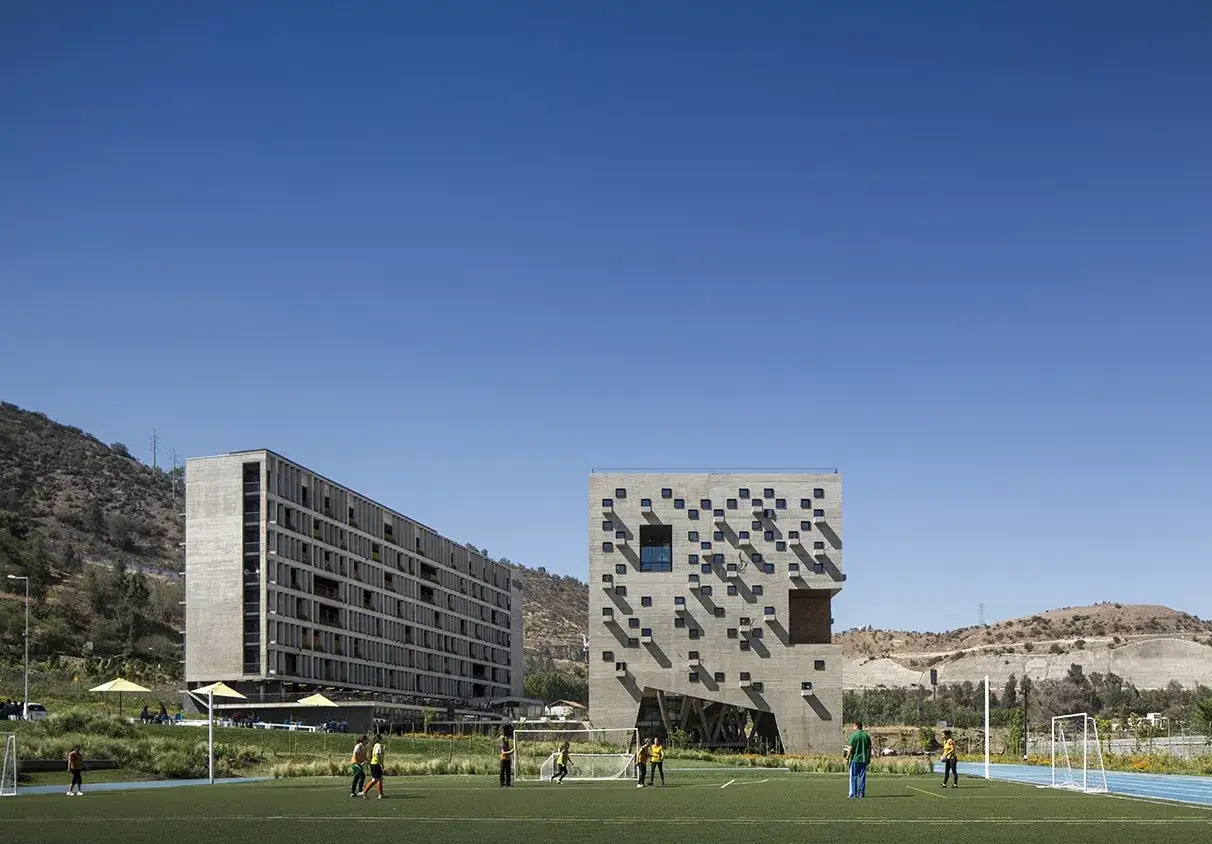 Bâtiments modernes sur le campus de l'université pontificale catholique du Chili, avec un terrain de football en premier plan.