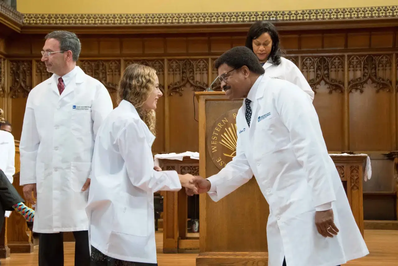 Cérémonie de remise des blouses blanches. Des étudiants en médecine, futurs médecins, se serrent la main. Un moment clé avant leur médecine à l'étranger.