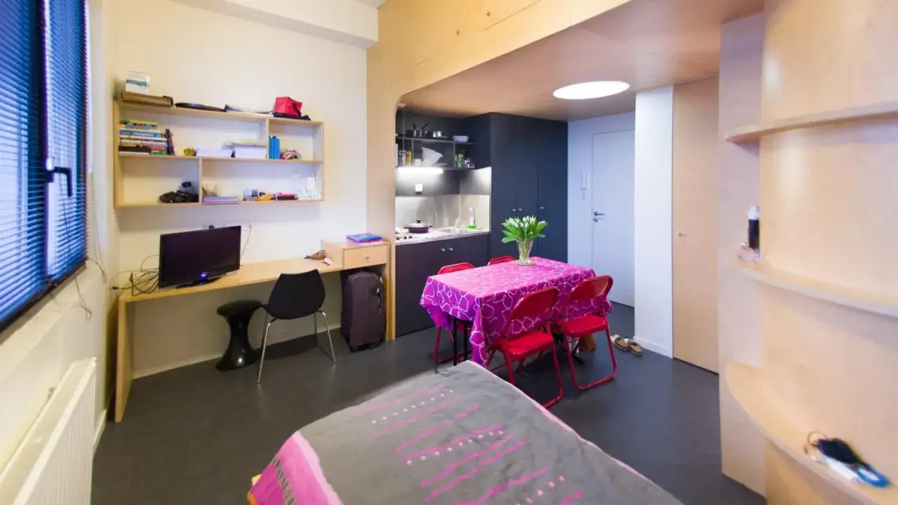Chambre d'étudiant aménagée pour une année sabbatique après le bac : coin bureau, kitchenette, table et lit.
