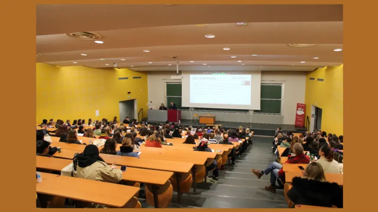 Amphithéâtre d'une école privée de psychologie en France, avec des étudiants attentifs et un professeur devant un écran.