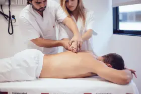 Des étudiants de l'école kine Gérone apprennent la kinésithérapie en pratiquant sur un patient allongé.