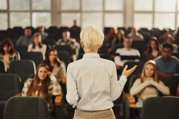 Professeure s'adressant à des étudiants dans un amphithéâtre, un lieu d'apprentissage pour une école de commerce publique gratuite.