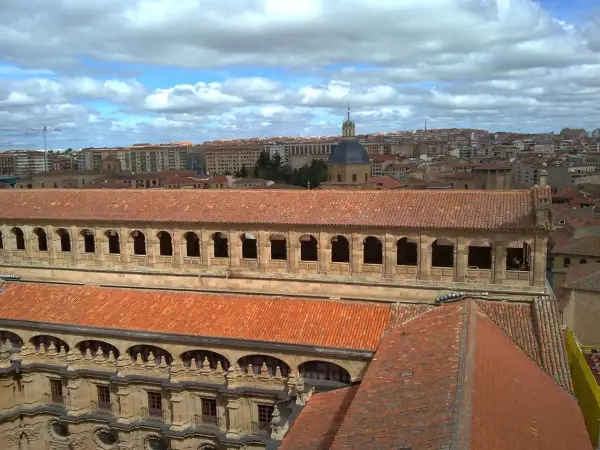 Vue aérienne de l'université pontificale de Salamanque, avec ses toits de tuiles rouges et son dôme emblématique sous un ciel nuageux.