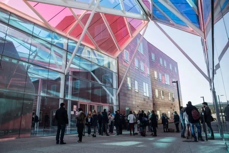 Étudiants devant le bâtiment moderne de l'ICN Business School, avec sa façade vitrée et son toit coloré.