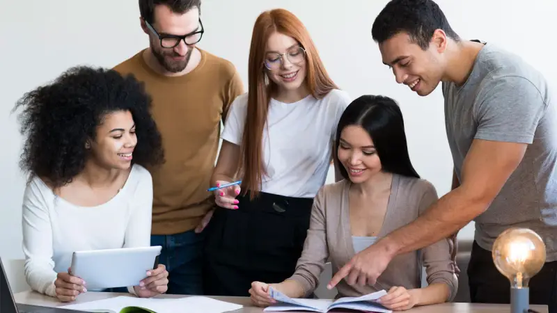 Une équipe diversifiée collabore sur un projet, comme un master moyen orient. Ils étudient des documents et utilisent une tablette.
