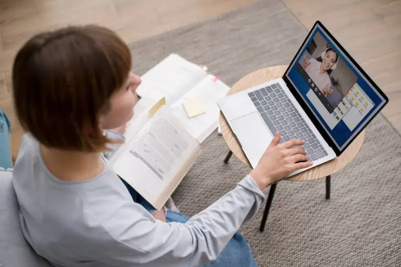 Étudiante en licence neurosciences à distance, elle étudie sur son ordinateur portable et des livres ouverts.