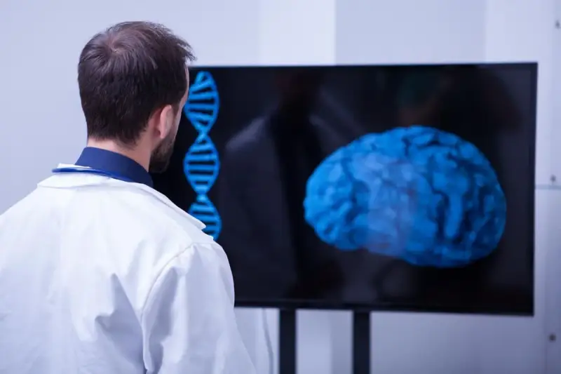 Un médecin observe un cerveau bleu et une double hélice sur un écran, signe d'une formation neuropsychologie à distance.